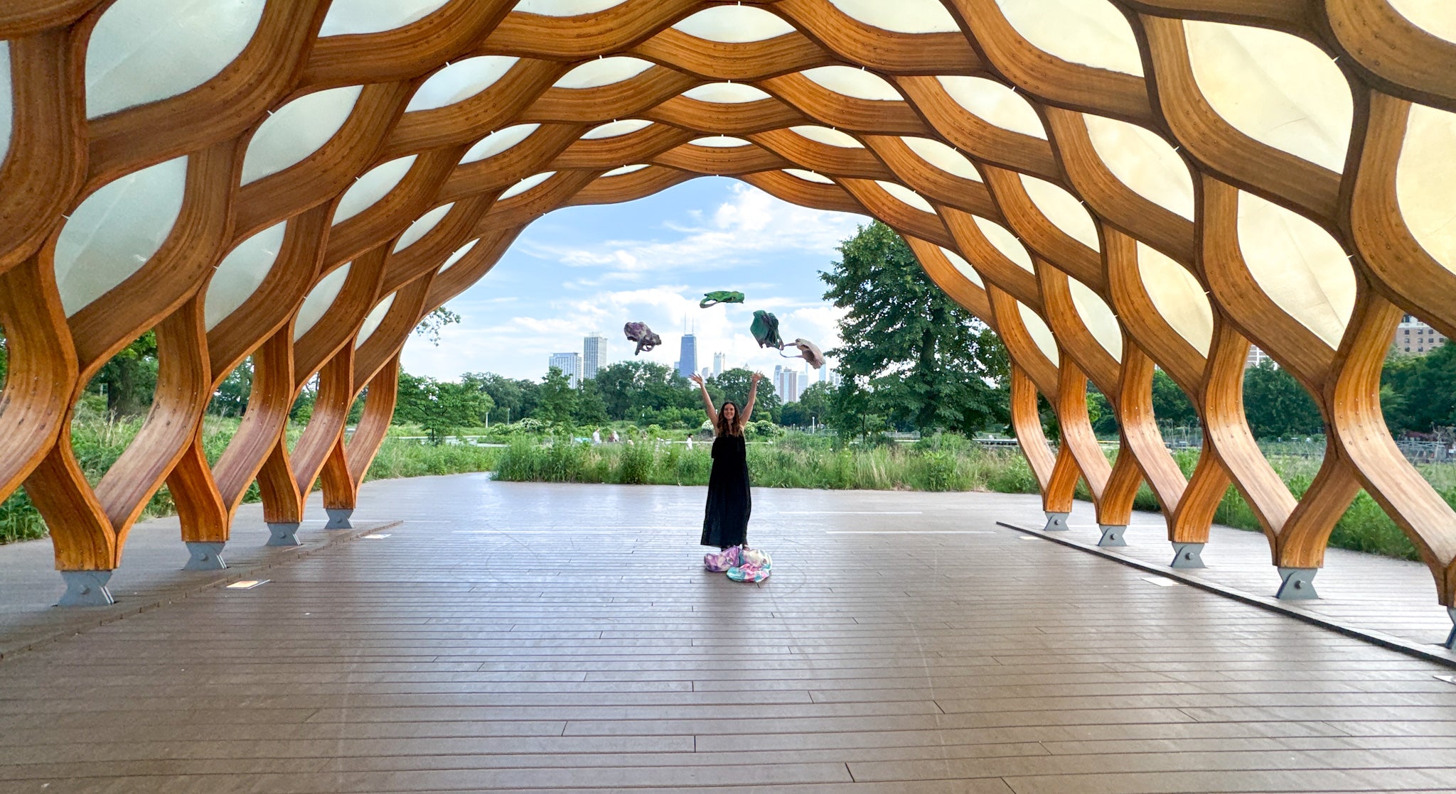 Modern architectural structure with wooden design, people in the background, founder with tie-dye tote bags